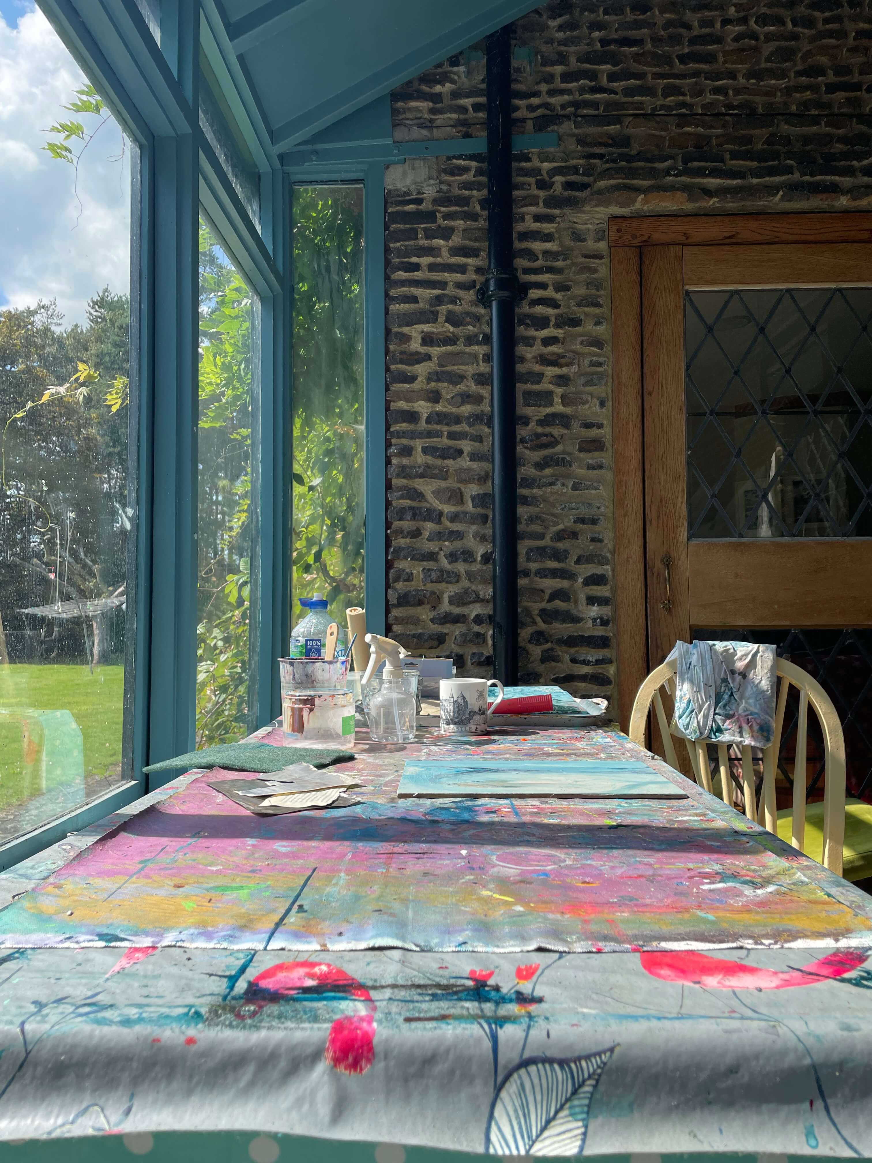 Art studio workspace with colourful paintings and supplies